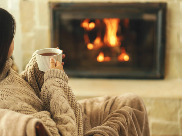 Girl sitting in front of fireplace with coffee/tea saving electricity 