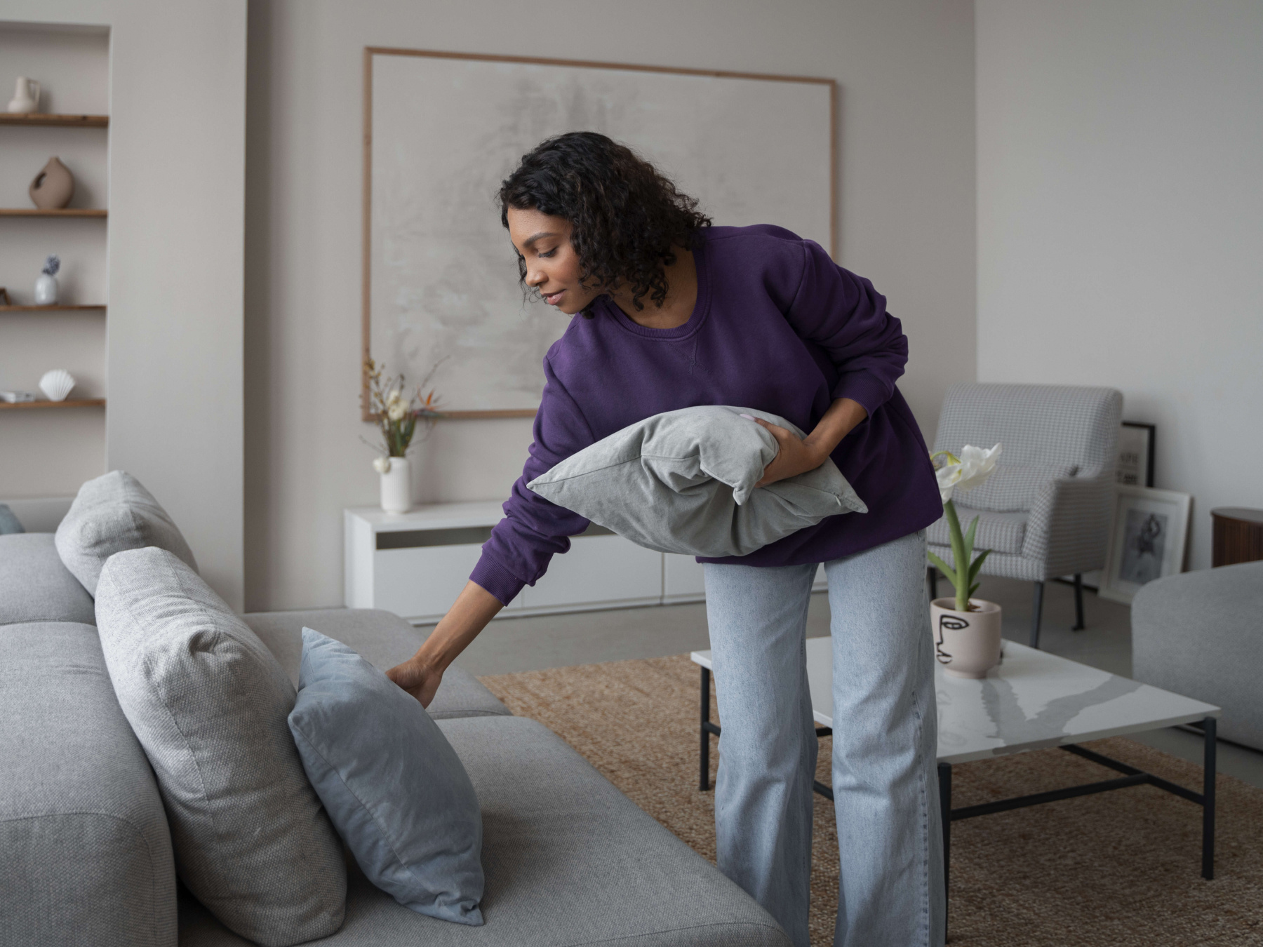 Woman places scatter cushions on a couch