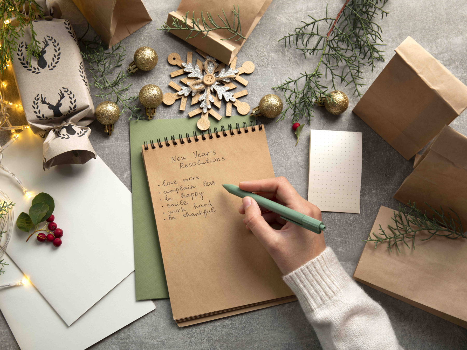 Writing New Year's Resolutions surrounded by festive gifts and decor